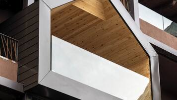 A modern building with a unique geometric balcony design, featuring a combination of metal and wooden materials.