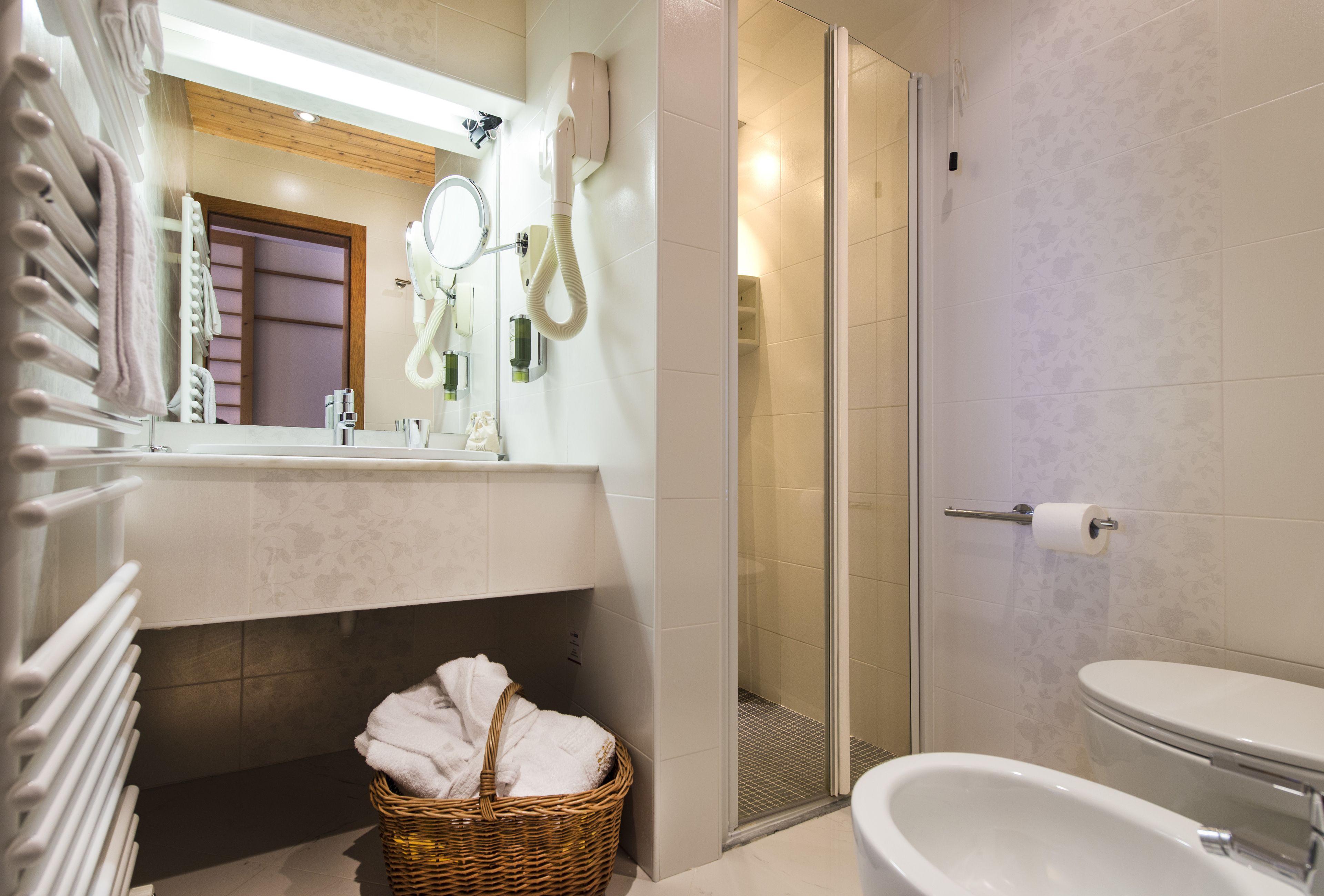 Une salle de bain avec douche, toilettes et un panier en osier contenant des serviettes.