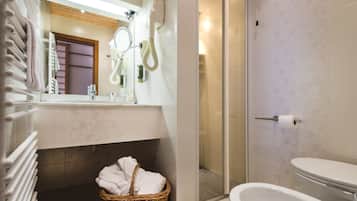 Une salle de bain avec douche, toilettes et un panier en osier contenant des serviettes.
