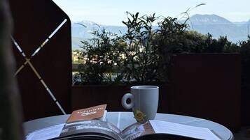 Ein Tisch mit einem Buch und einer Tasse auf einem Balkon mit Blick auf Berge.