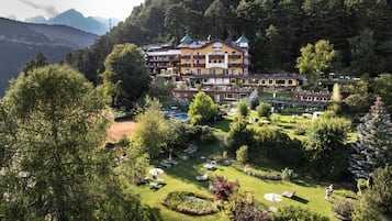 A hotel with multiple balconies, a swimming pool, and a well-maintained garden.