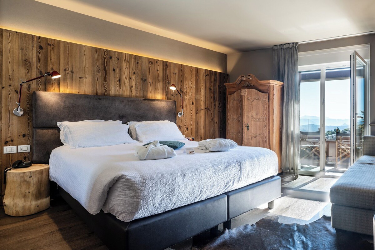 Une chambre d’hôtel moderne dotée d’un grand lit, d’un canapé, d’un bureau avec un ordinateur et offrant une vue sur l’extérieur.