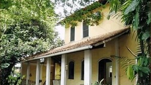 Une maison dotée d’un porche abrité, de colonnes et d’un jardin.