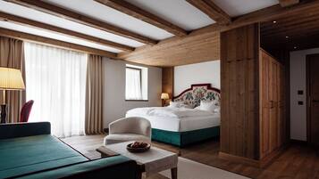 Quarto de hotel com cama, uma cadeira, uma mesa e um guarda-roupa de madeira.