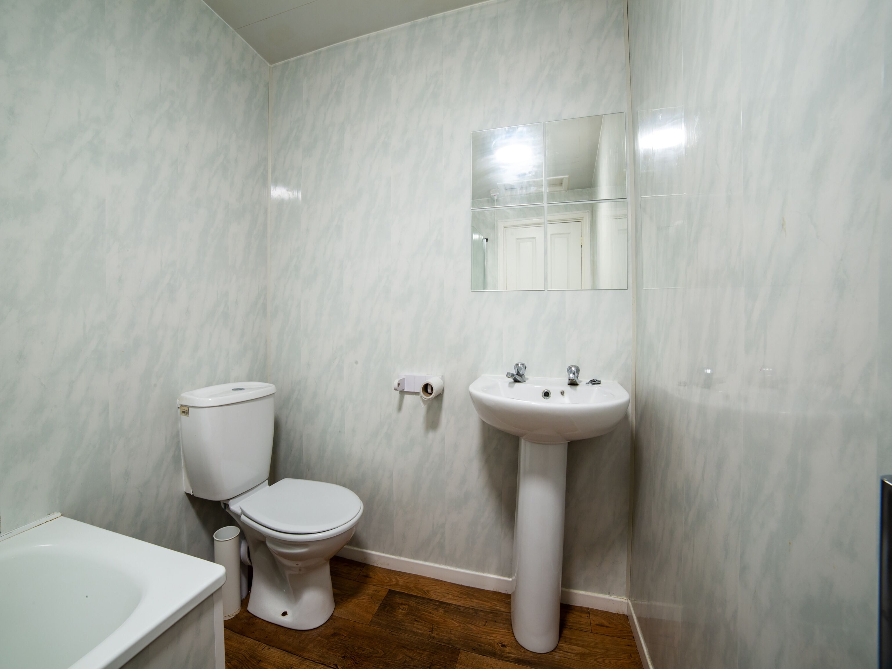 A bathroom with a toilet, sink, and mirror.