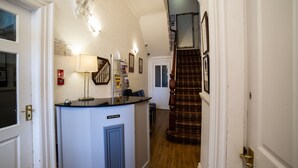 A reception area with a reception desk, a staircase, and a door leading to another room. - The Douglas Hotel (Hartlepool)