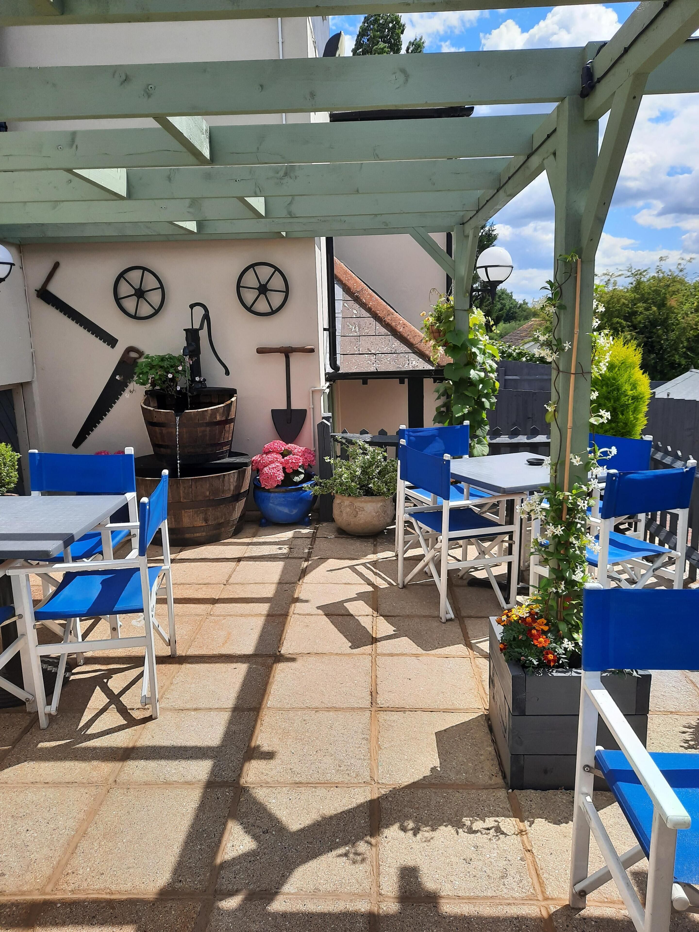 An outdoor patio with blue and white chairs, a table, and potted plants.