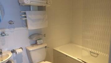 A bathroom with a toilet, sink, and bathtub. There are towels and toiletries on the wall.