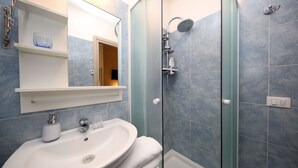 A bathroom with a white sink, a glass shower enclosure, and a mirror above the sink. - Tibullo Guesthouse (Rome)