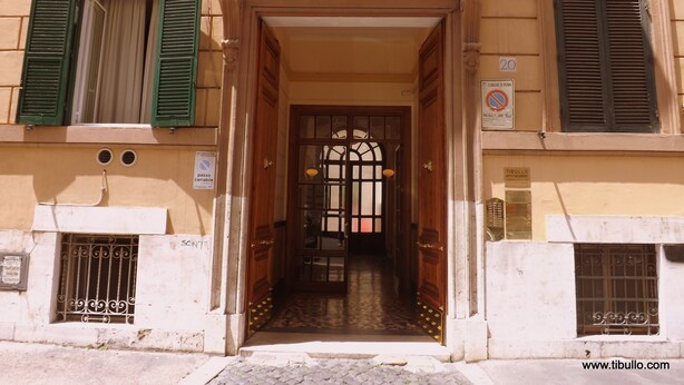 A building entrance with a wooden door, green shutters, and a tiled floor. - Tibullo Guesthouse (Rome)