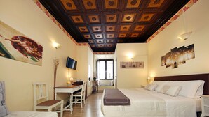A hotel room with a wooden ceiling, a bed, a desk, and a chair. - Tibullo Guesthouse (Rome)