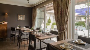 Un comedor con mesas dispuestas para dos, un armario de madera y vistas al exterior.