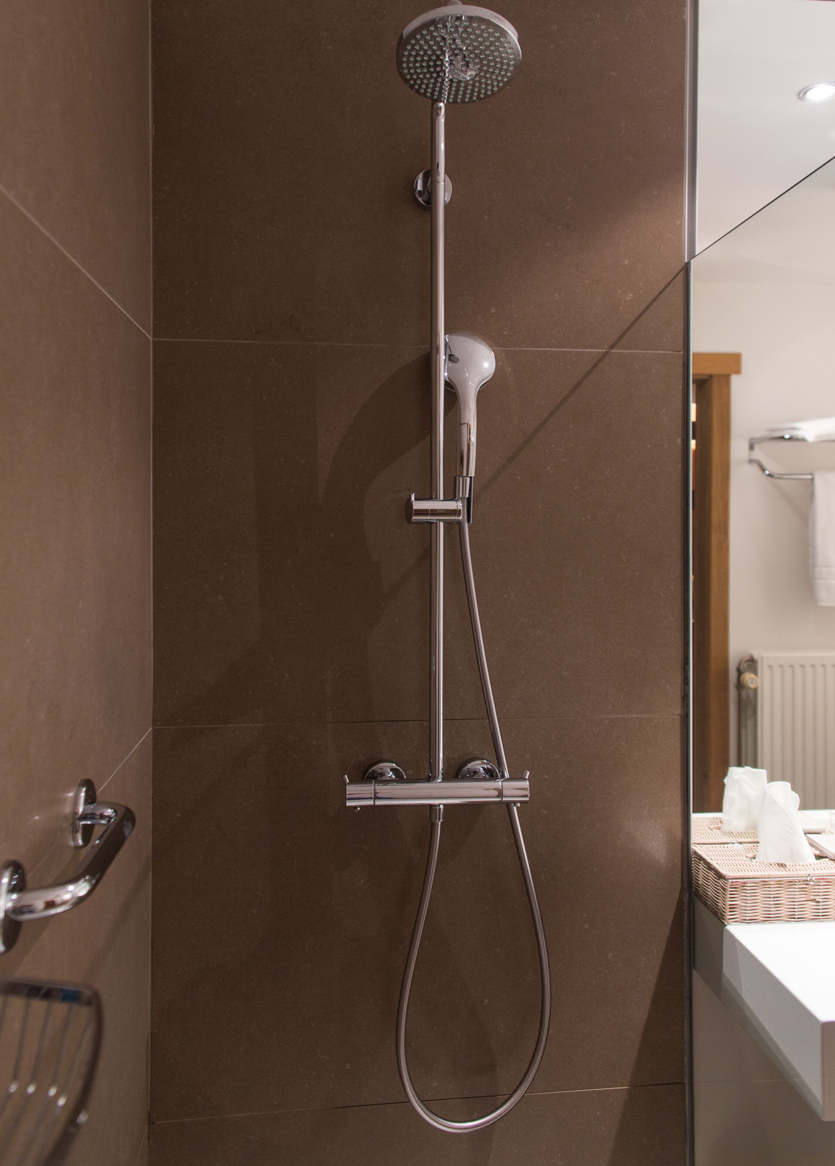 A modern bathroom with a shower, a mirror, and a towel rack.