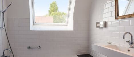 Ein modernes Badezimmer mit Oberlicht, einer Badewanne, einem Waschbecken und einer Dusche.