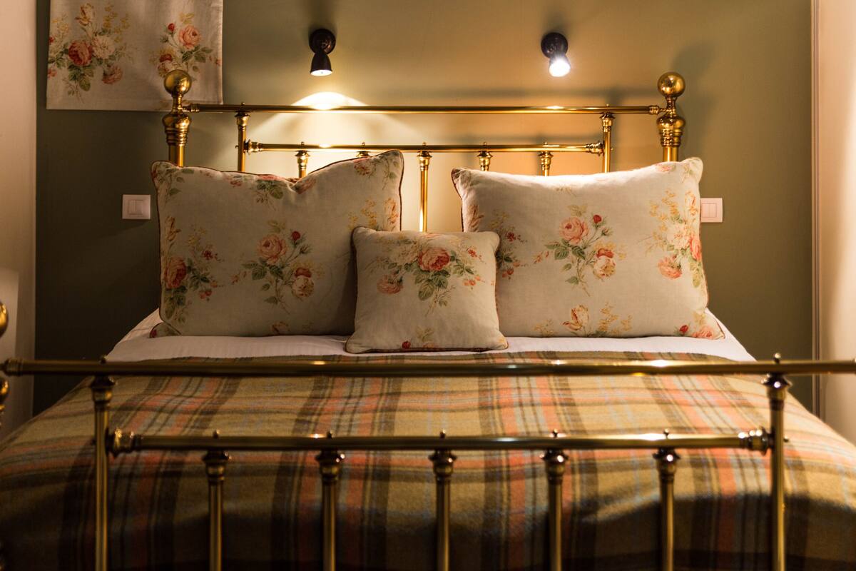 A bed with floral-patterned pillows and a plaid bedspread.