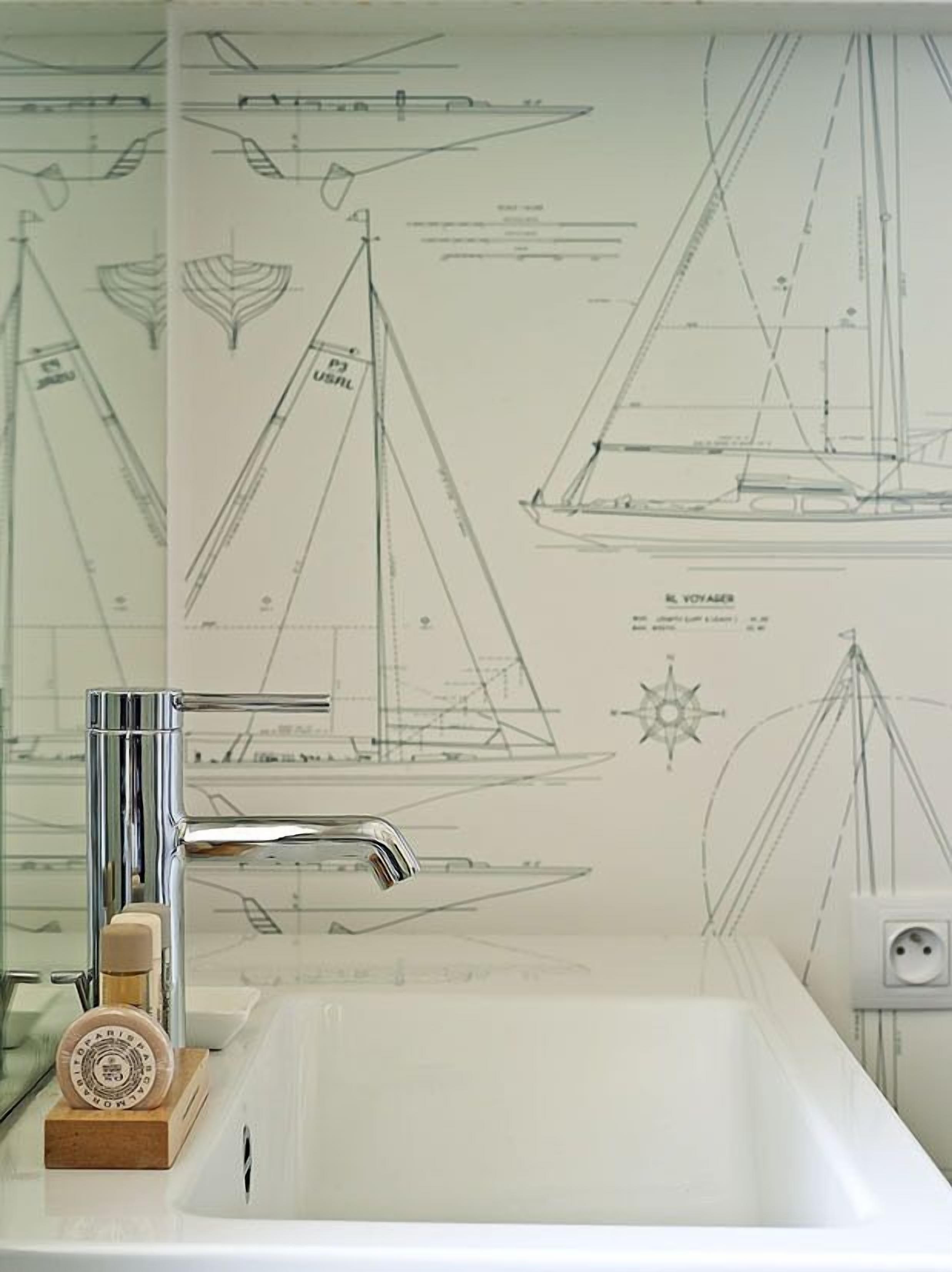 Ein Badezimmer mit Waschbecken, Spiegel und einer Wand mit Segelboot-Zeichnungen.