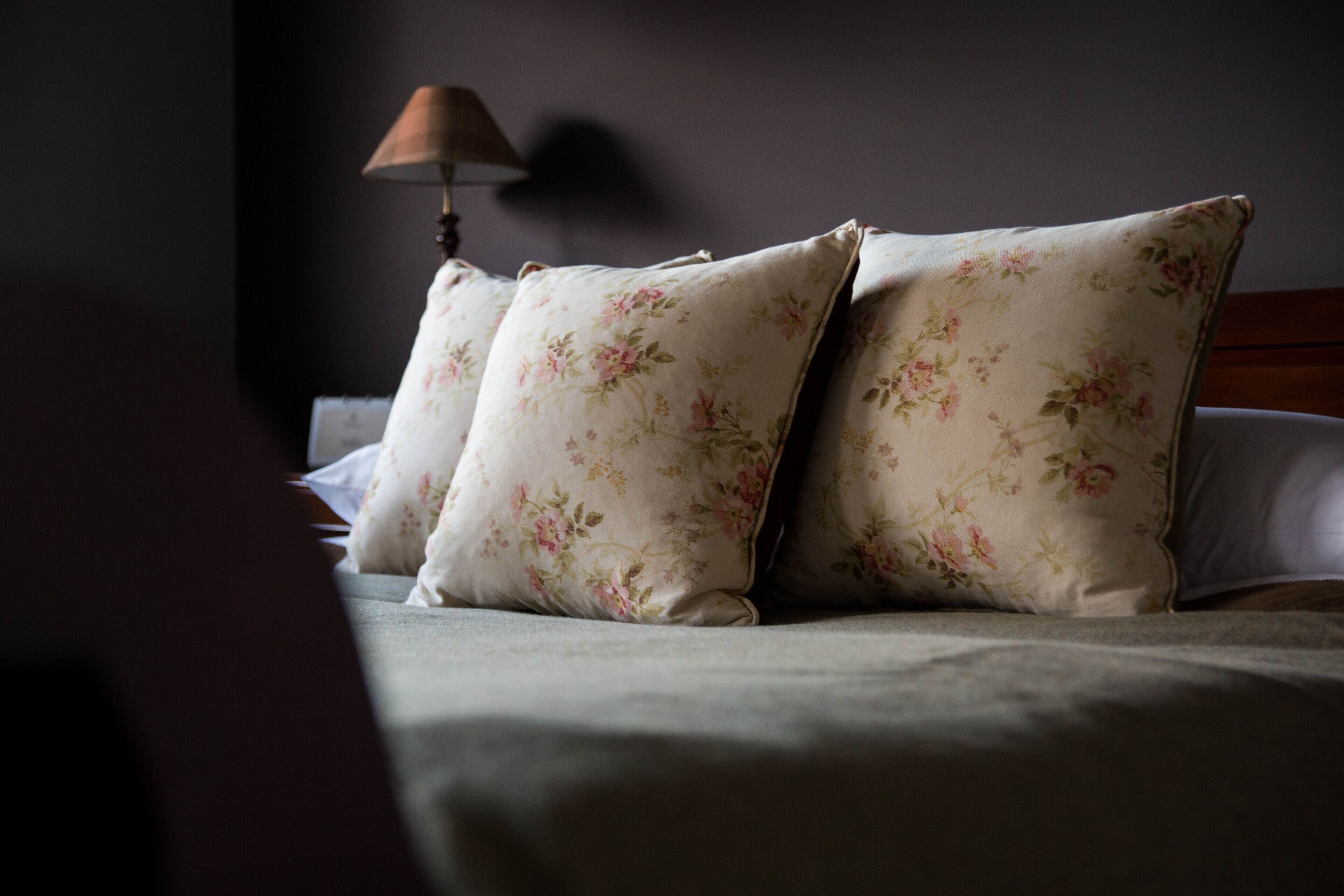Un lit avec des oreillers à motifs floraux et une tête de lit en bois.