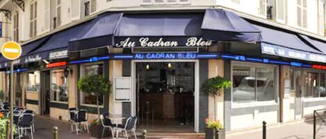 Un restaurante llamado 'Au Cadran Bleu' con terraza y un letrero que indica restaurante y hotel.