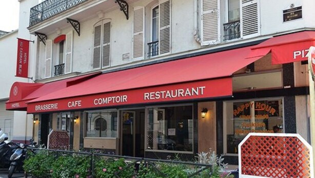 Un restaurant avec un auvent rouge sur lequel on peut lire les inscriptions « COMPTOIR RESTAURANT » et « CAFÉ-BRASSERIE ».