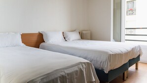 Deux lits simples dans une chambre avec une literie blanche et une tête de lit en bois.