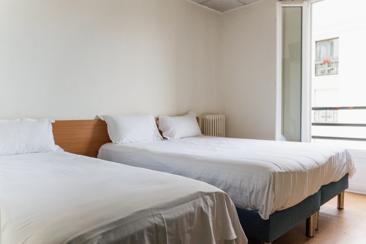 Two single beds in a room with white bedding and a wooden headboard.