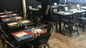 L’intérieur d’un restaurant, avec des tables dressées pour le service, des chaises et une personne debout près des tables.