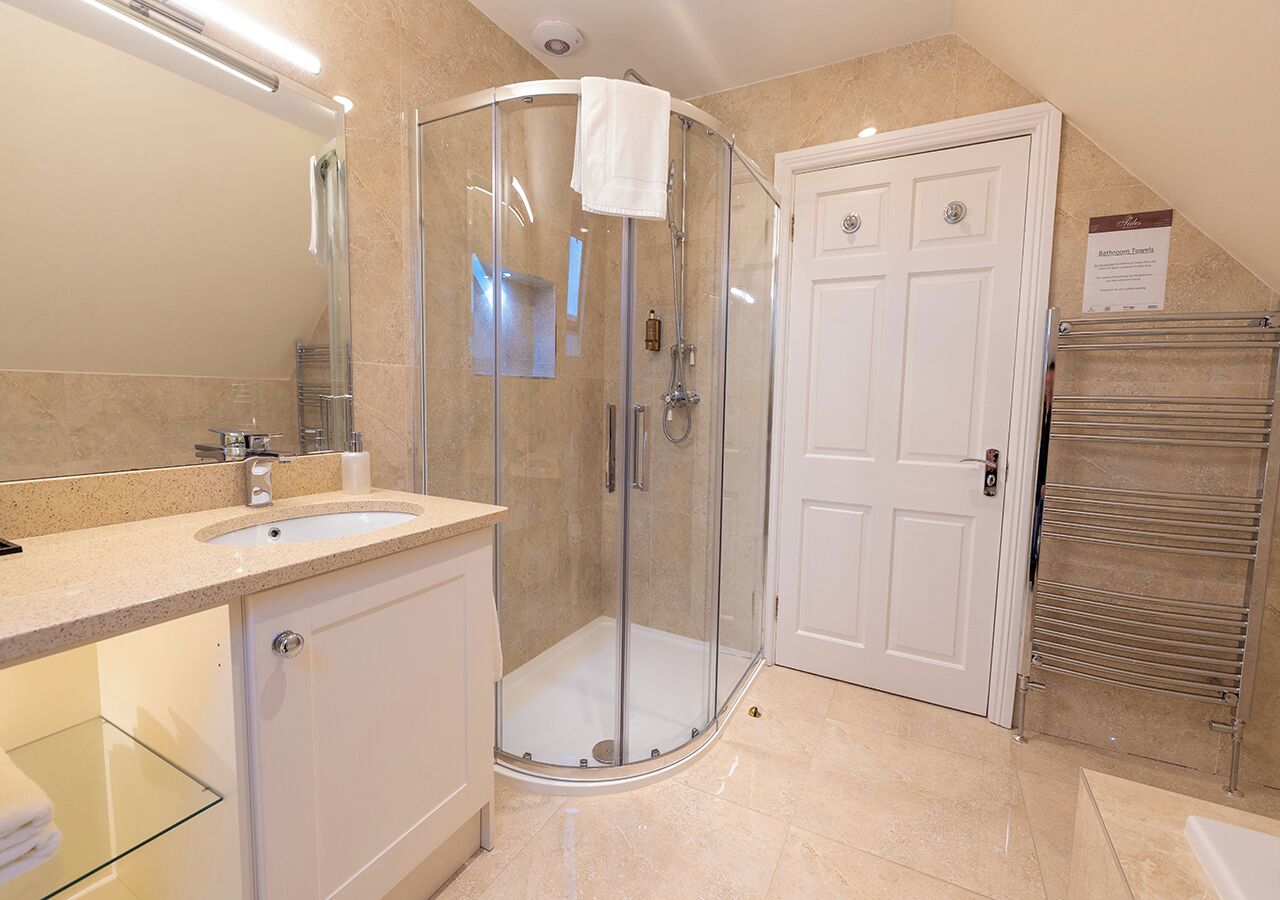 Un baño moderno con cabina de ducha de vidrio, un lavabo blanco y un perchero para toallas.