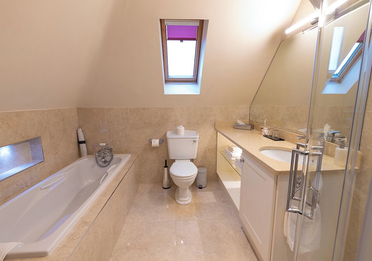 A modern bathroom with a bathtub, toilet, and shower area.