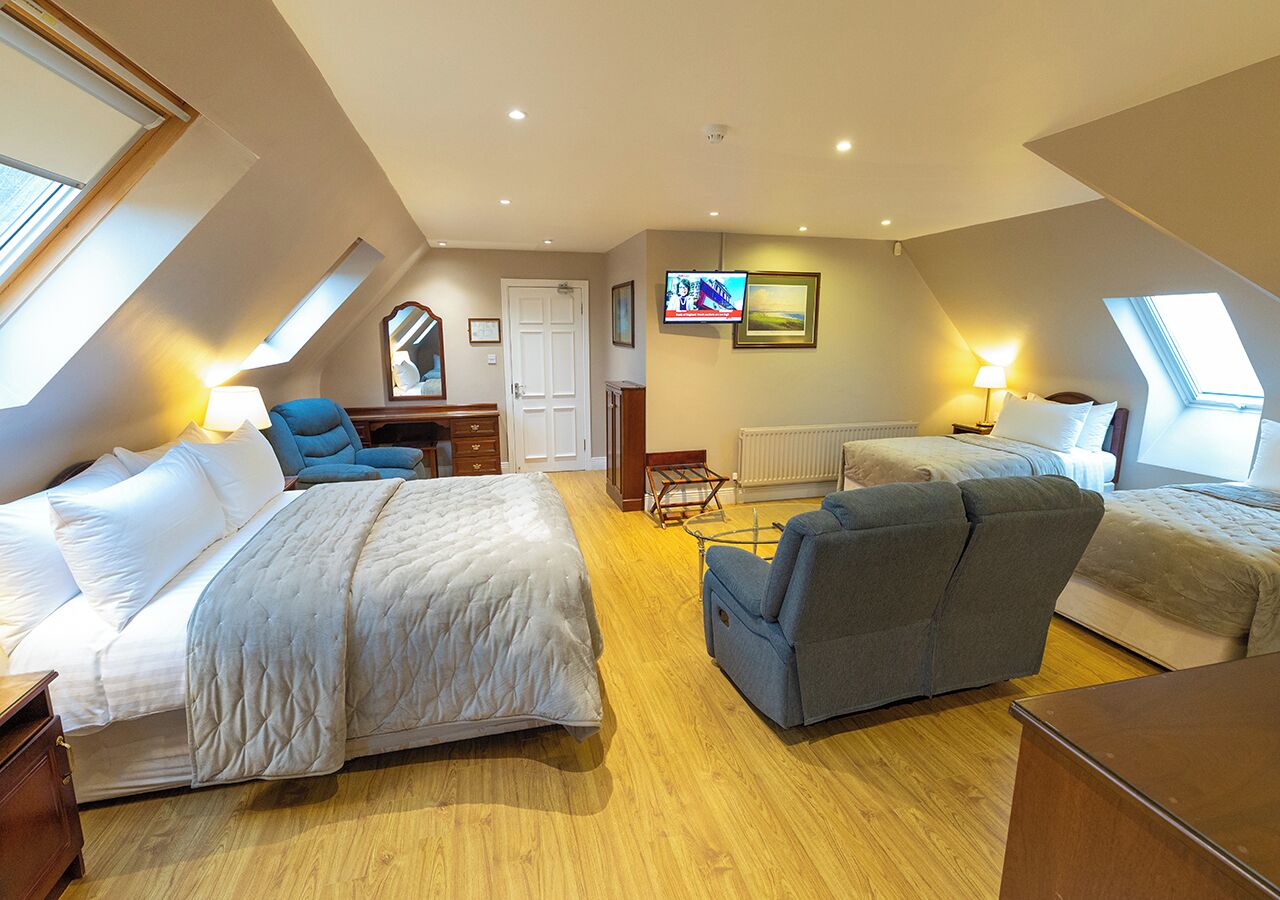 A room with two beds, a desk, a chair, and a television.