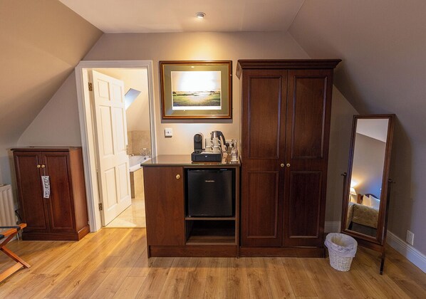 Una habitación con kitchenette, un refrigerador, un armario de madera, un cuadro en la pared y un espejo.