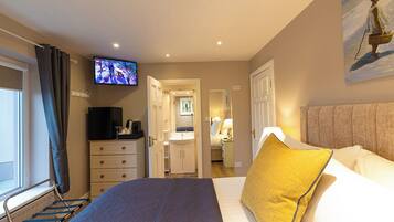 Una habitación de hotel con cama, televisión, baño y un cuadro en la pared.