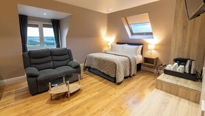 Een moderne hotelkamer met een bank, bed, nachtkastjes, koffiezetapparaat en dakraam.