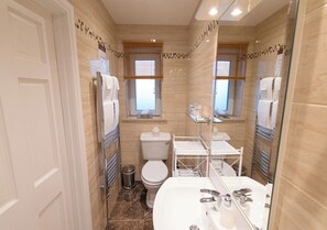 A bathroom with a toilet, sink, and glass shower enclosure. - The Tides B&B (Ballybunion)