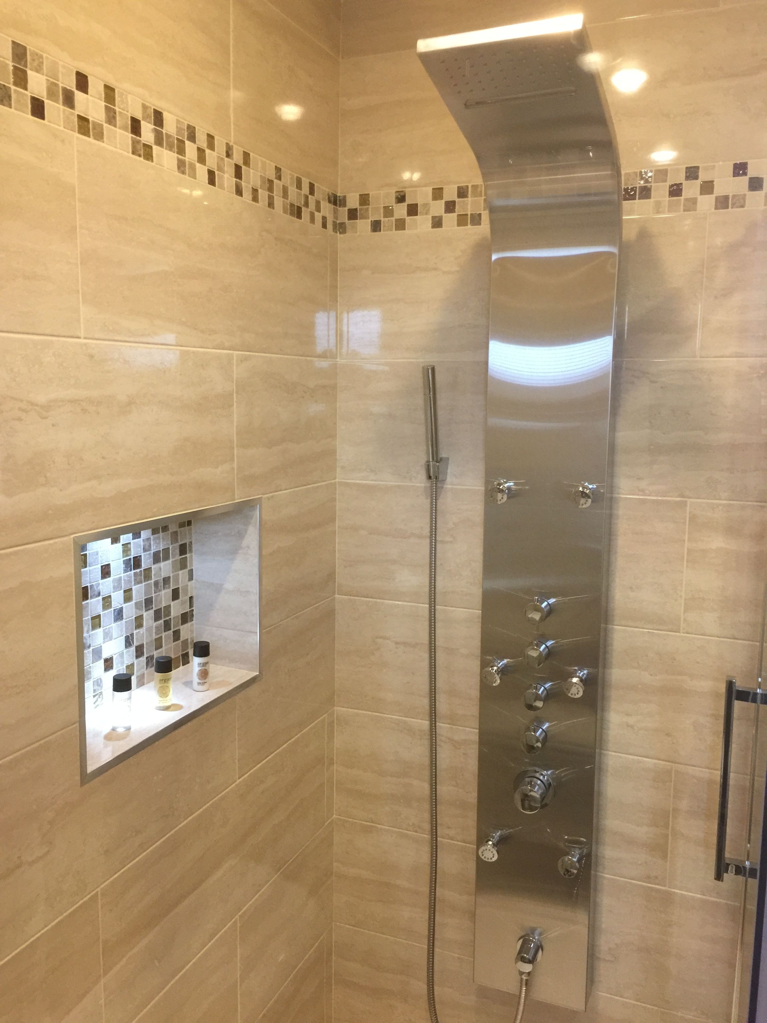 Une douche moderne dotée d’une paroi en verre, d’un panneau de commande avec plusieurs boutons et d’une étagère pour les articles de toilette.