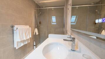 Un bagno moderno con un lavandino ampio, un box doccia in vetro e un portasciugamani con asciugamani bianchi.
