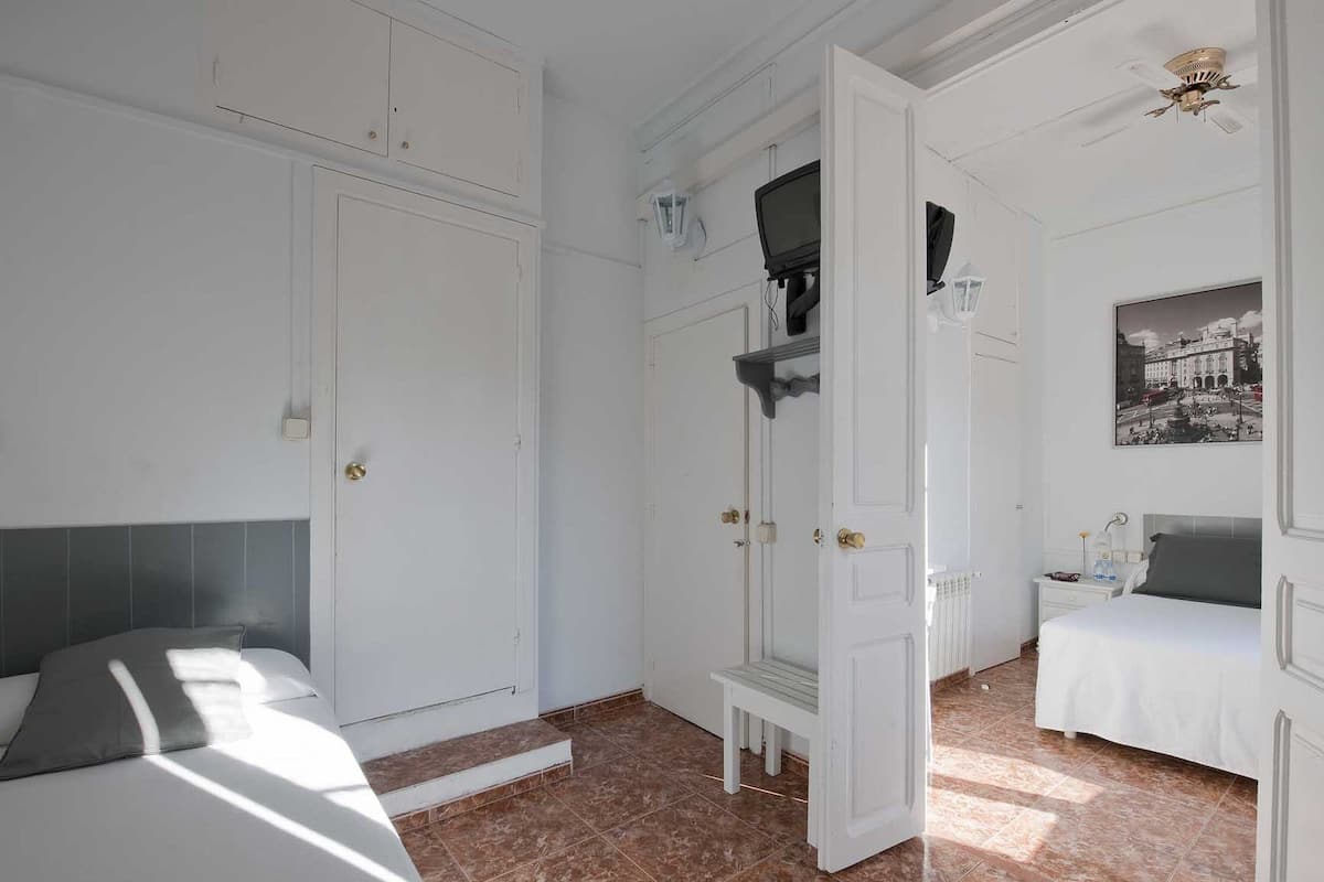 Un dormitorio con cama, mesita de noche, silla, armario y un cuadro en la pared.