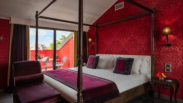 Una cama con dosel, con una decoración en rojo y blanco, una silla de madera y una mesita de noche con una lámpara.