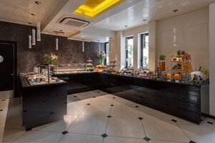 Una barra de desayuno moderna con diversas opciones de comida y bebida, como pasteles, frutas y refrescos.