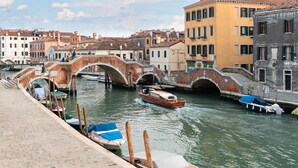 Um canal com barcos, uma ponte e edifícios históricos.