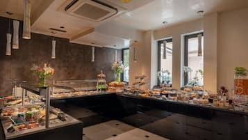 Un área de bufé con diferentes opciones de comida, una estación central de servicio y lámparas colgantes.