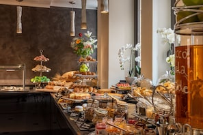 Un bufé con diversos alimentos, entre ellos bollería, frutas y salsas.