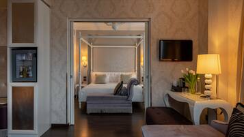 A hotel room with a bed, a desk with a lamp, a television, and a minibar.