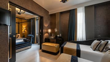 A hotel room with a large bed, a sofa, a small table with a lamp, and a mirror.