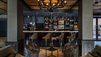 A bar area with a central bar, multiple seating options, and a variety of bottles on shelves.