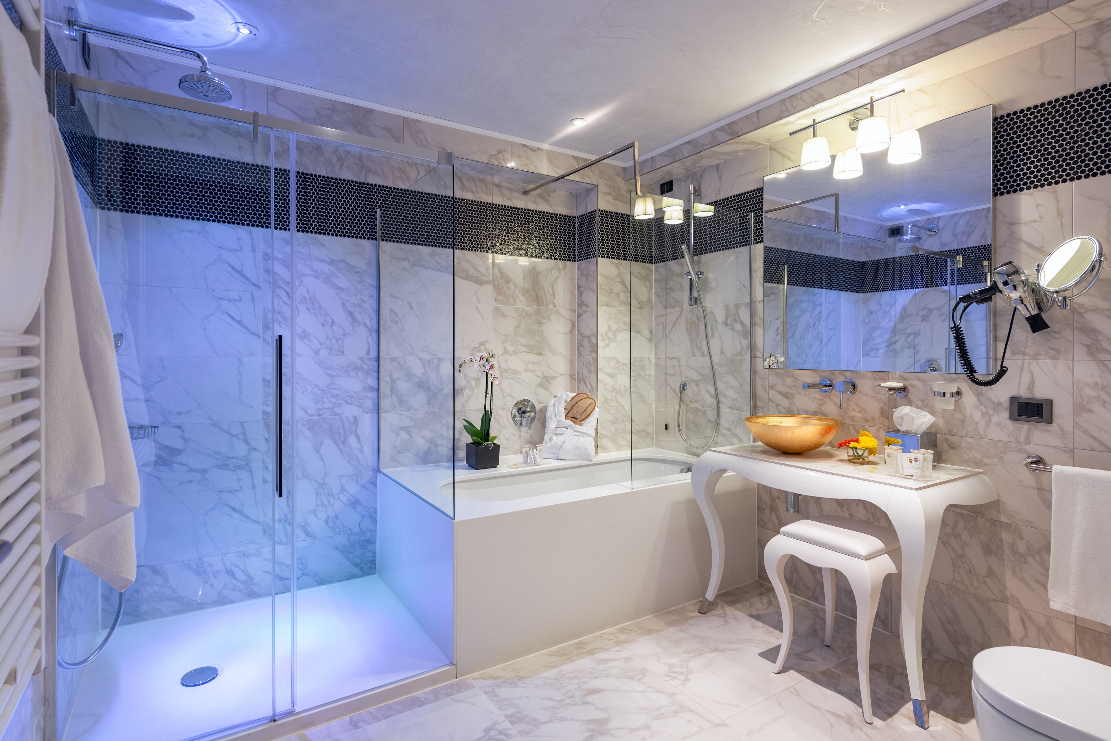 Ein modernes Badezimmer mit einer gläsernen Duschkabine, einem weißen Waschtisch und einem großzügigen Becken sowie einem Spiegel über dem Waschtisch.