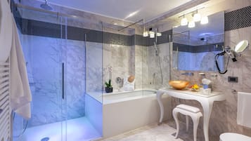 Ein modernes Badezimmer mit einer gläsernen Duschkabine, einem weißen Waschtisch und einem großzügigen Becken sowie einem Spiegel über dem Waschtisch.