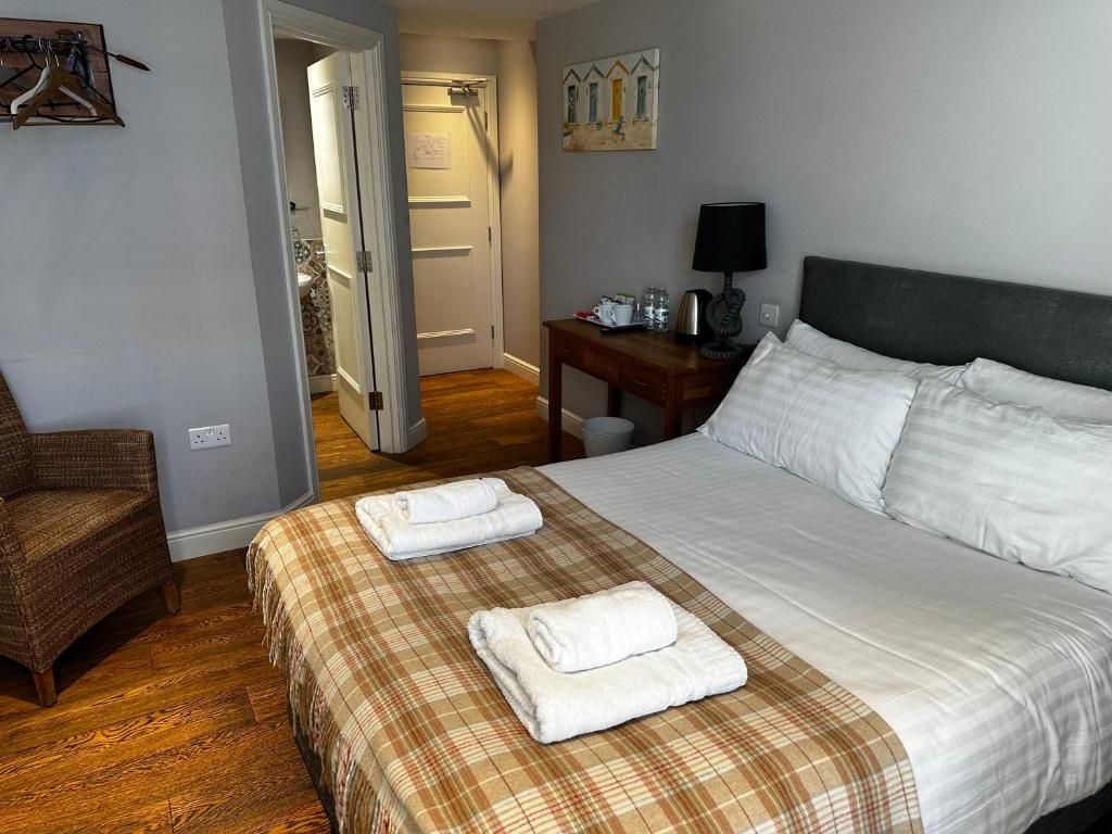 A hotel room with a bed, a chair, a desk, and a painting on the wall.