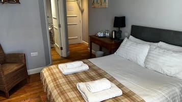 A hotel room with a bed, a chair, a desk, and a painting on the wall.
