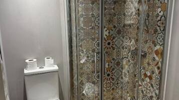 A shower enclosure with a glass door and a showerhead.