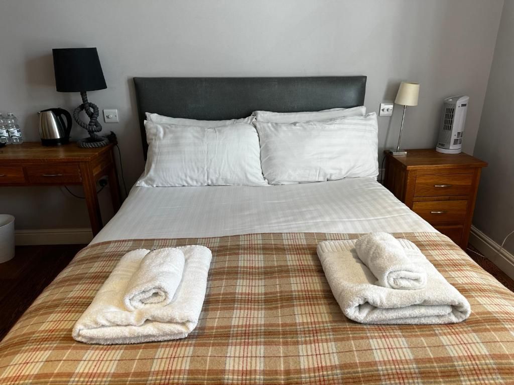 A hotel room with a bed, two bedside tables, a lamp, a kettle, and a coffee maker.